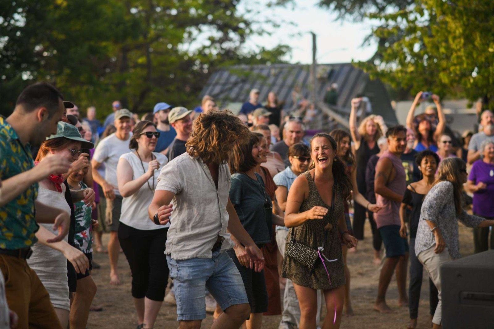 A crowd dancing in golden evening light at the Summer Outdoor Concert Series on Salt Spring Island